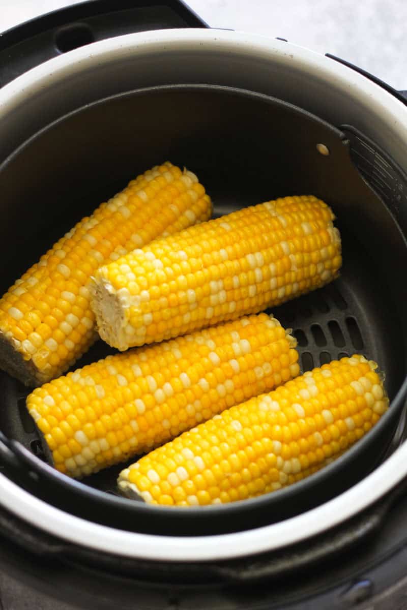 Four fresh corn cobs cooked in an air fryer for a healthy snack or meal.