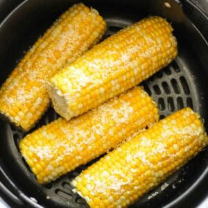 Fresh grilled corn on the cob with salt in a black grill basket.
