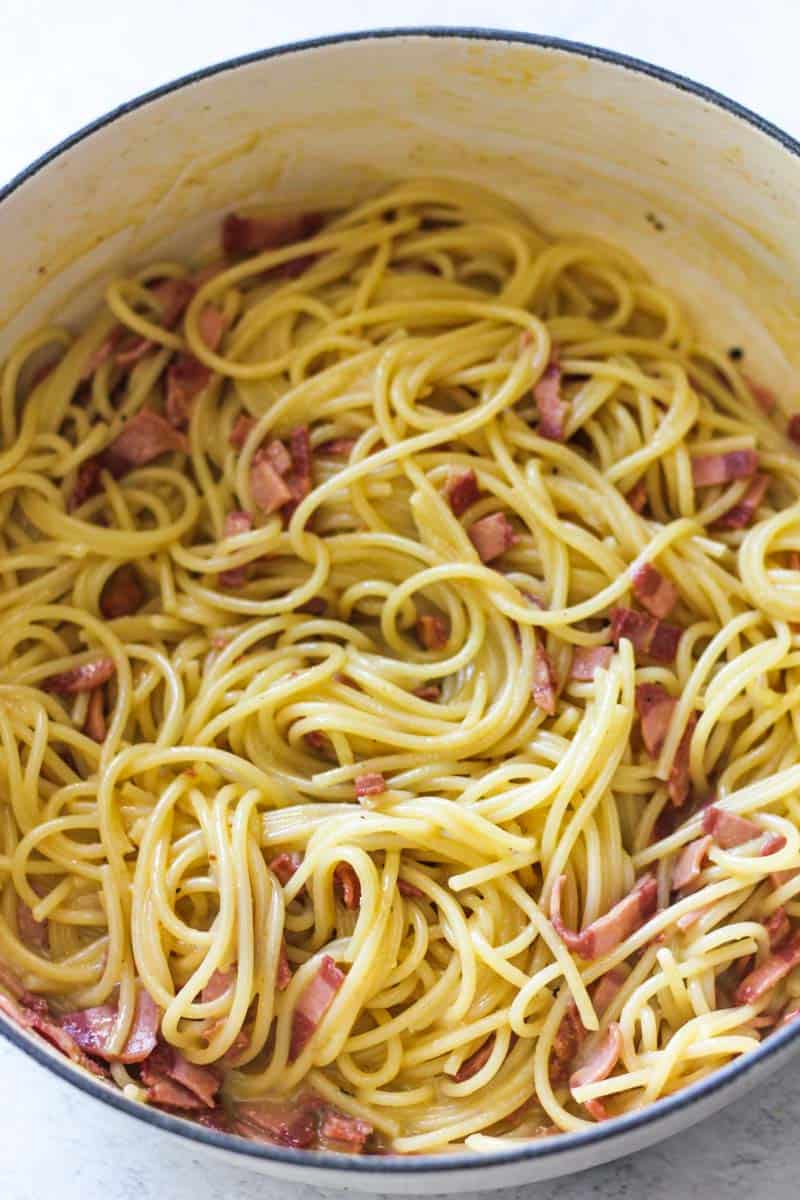 Close-up of spaghetti with bacon and creamy sauce in a bowl.