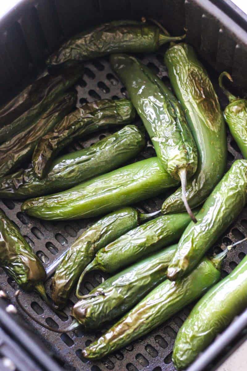 Fresh green chili peppers in a basket, ready for culinary use.