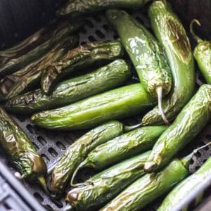 Close-up of roasted green chili peppers on a grill rack.