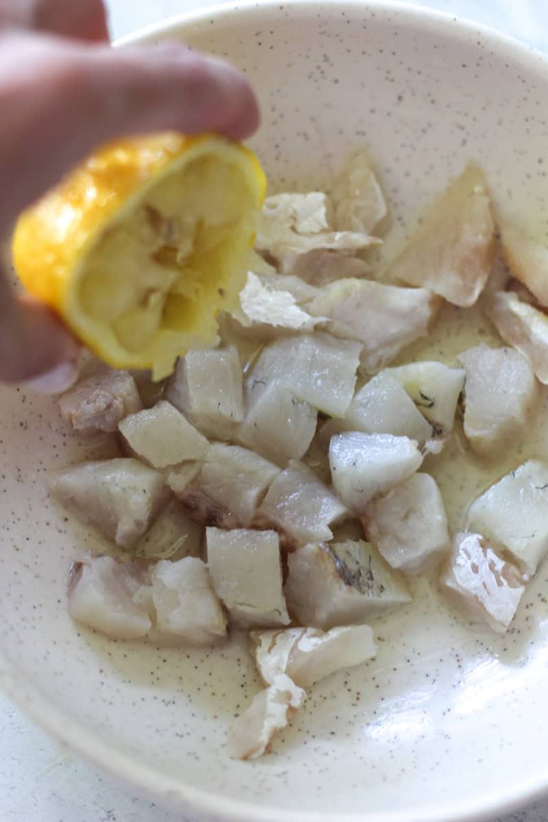 Close-up of fish pieces with lemon in a bowl for seafood meal.
