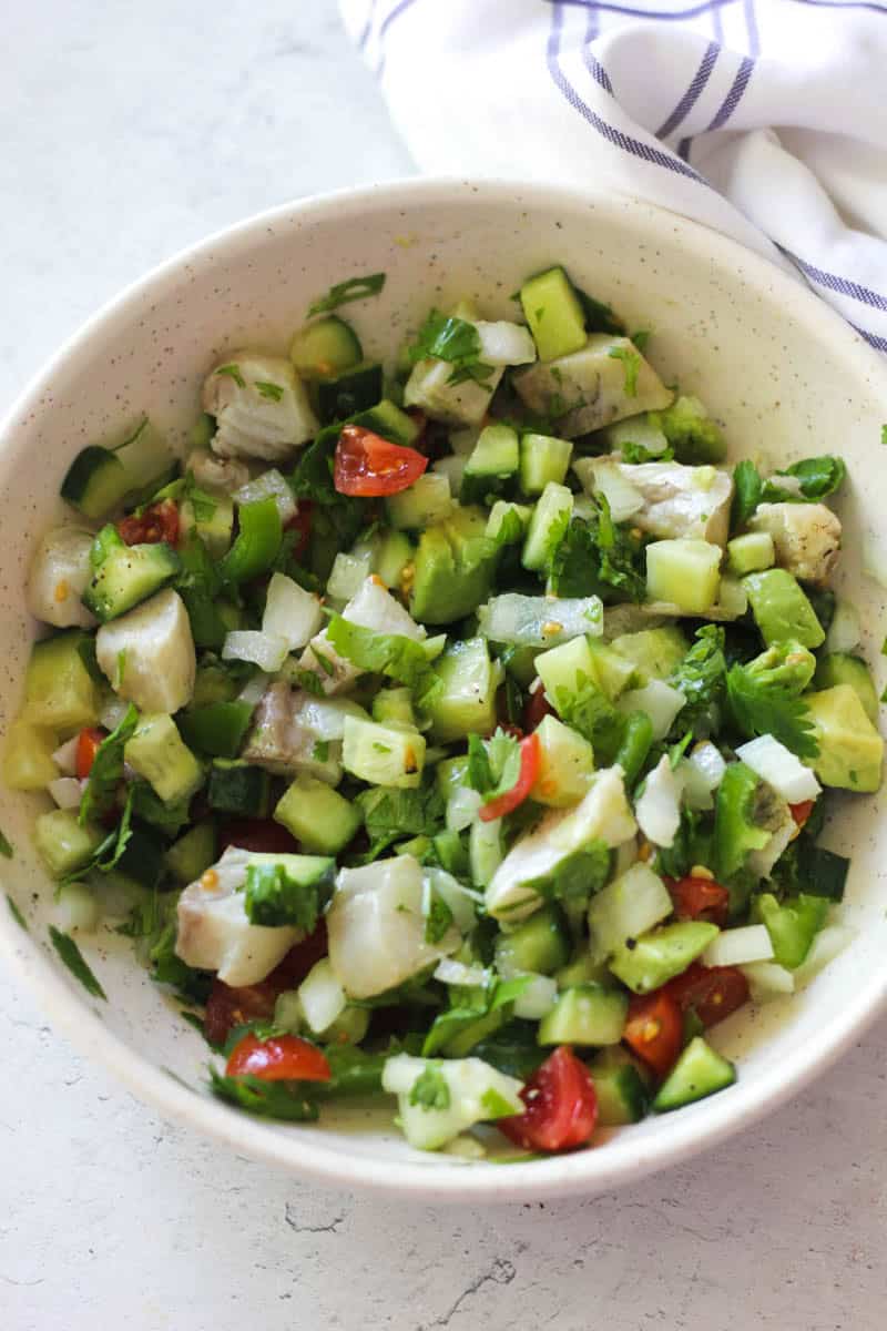 Healthy cucumber and chicken salad with cherry tomatoes and herbs in a bowl.