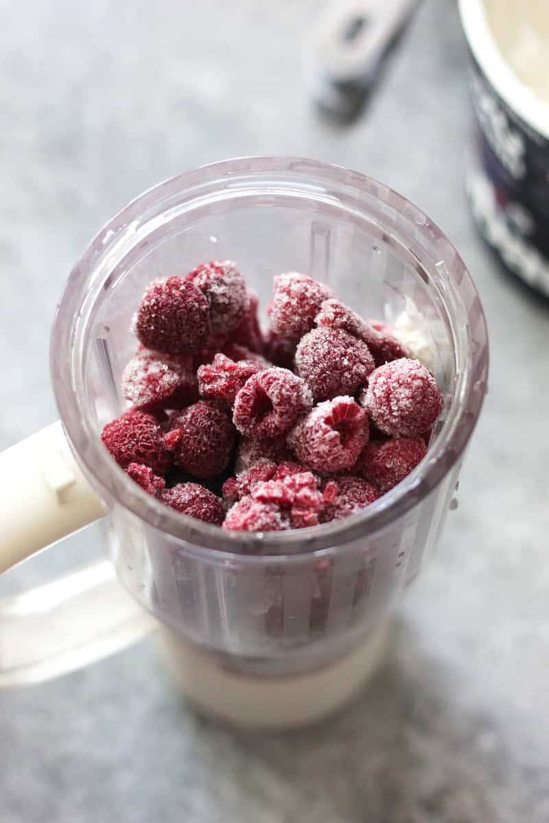 Frozen raspberries in a blender for smoothie topping or dessert.