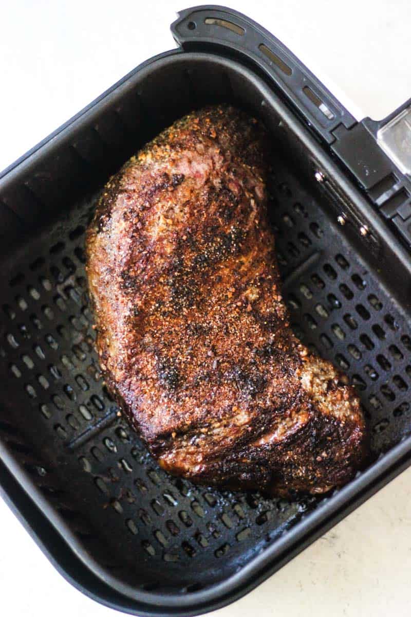 Smoked grilled steak in air fryer basket with seasoned crust.