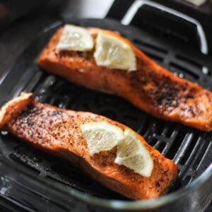 Grilled salmon fillets with lemon wedges on a grill pan.