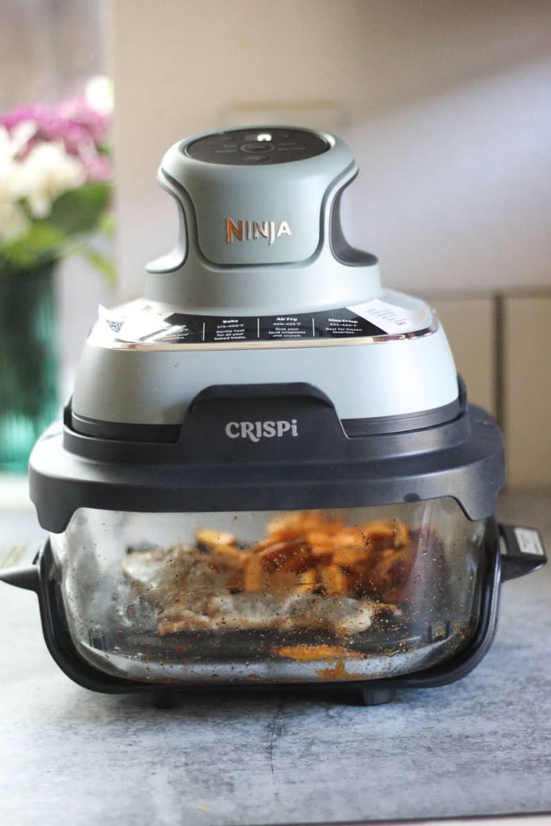 The Top Meal Ninja CRISPi air fryer roasting vegetables and chicken on countertop.