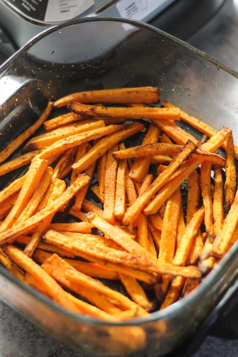 Crispy oven-baked sweet potato fries in a black air fryer basket.