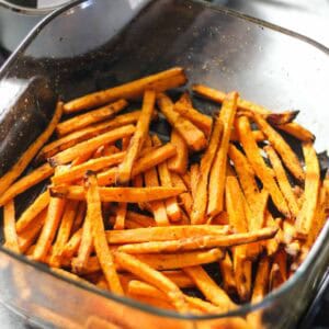 Crispy orange sweet potato fries in a glass baking dish.